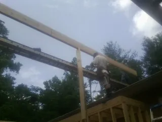 Carpenter setting a ridge beam over a new addition frame — Ice Dam Removal by Roofing Brothers in Osco