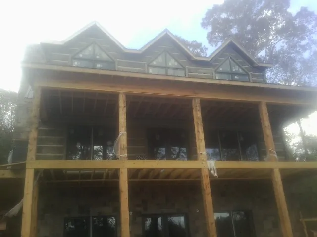 Dormers and porch framing on a large log home under construction — Roof Coating work by our crew in Osco