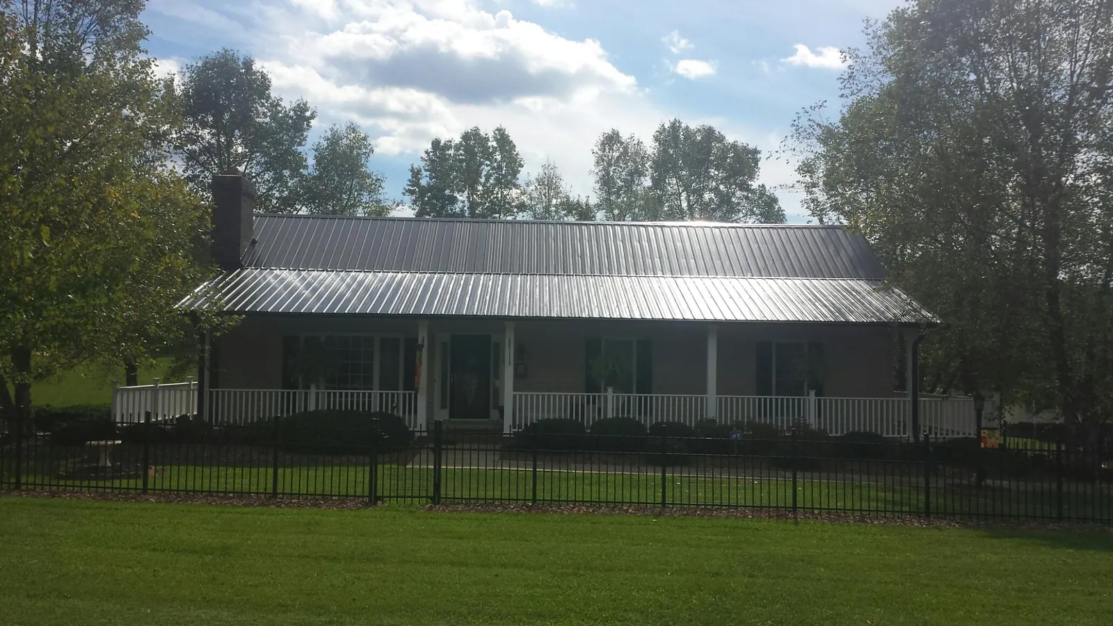 Gray metal roof on a brick ranch with a full width front porch — Gutter Guard Installation work by our crew in Osco