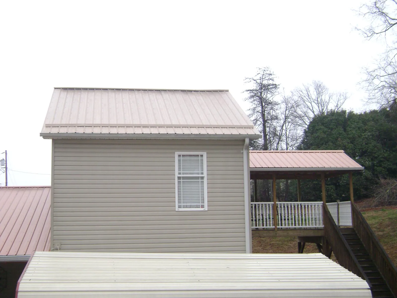 Tan metal roofs on a two story addition and attached porch, from a Roof Replacement job in Osco