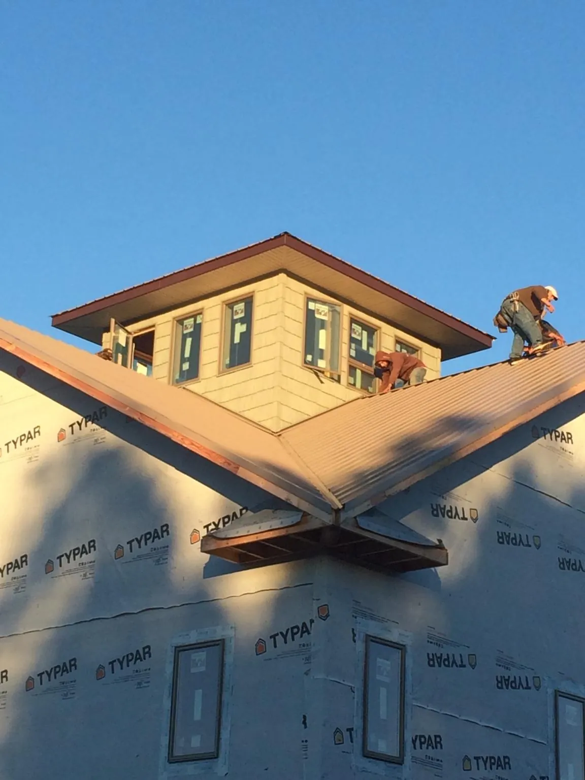 Roofers working around a rooftop cupola on a new metal roof at sunset — Roof Waterproofing in Osco by Roofing Brothers